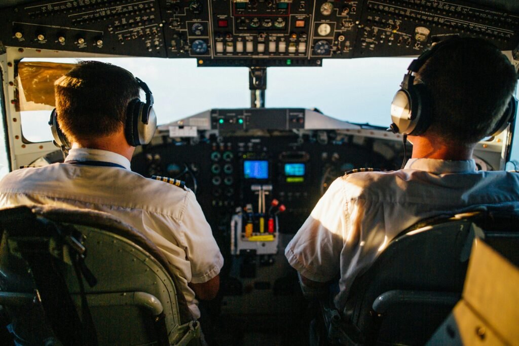 Two pilots in cockpit navigating airplane at high altitude, daylight